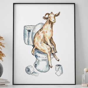 May include: A framed watercolor print depicts a goat sitting on a toilet. The goat is brown and tan, with a relaxed posture. The toilet is light blue and white, with two rolls of toilet paper on the floor. The print is displayed in a black frame.
