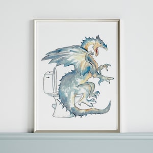 Puede incluir: Una pintura de acuarela de un dragón azul sentado en un inodoro blanco. El dragón tiene una barriga amarilla y naranja y está mirando hacia la derecha. La pintura está enmarcada en un marco plateado.