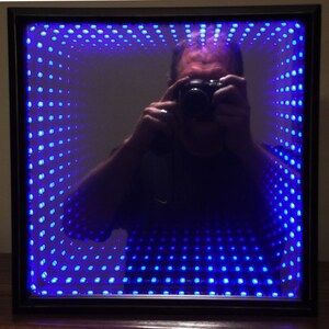 Blue infinity mirror.  Approximately 3 inches thick.  9v battery powered.  Set in a black/bronze shadow box.  Lit with blue LEDs