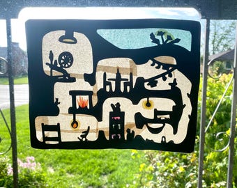 May include: A black and white paper craft design with a maze-like pattern. The design features a wheel, a fire, and a ladder. The design is on a white background.