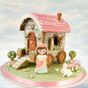 Puede incluir: Una casa de jengibre con forma de carro con un techo rosa y bordes blancos. La casa está decorada con flores y una niña pequeña con un vestido rosa. La casa está sobre un soporte para pasteles con una base de hierba verde y una cinta rosa.