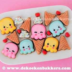 May include: A collection of decorated sugar cookies shaped like ice cream cones and ice cream with cute faces. The cookies are decorated with pink, blue, yellow, and white icing. The cookies are arranged on a white plate.