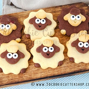 May include: Six brown and white sugar cookies shaped like sheep with black eyes and white icing. The cookies are arranged on a wooden chopping board.