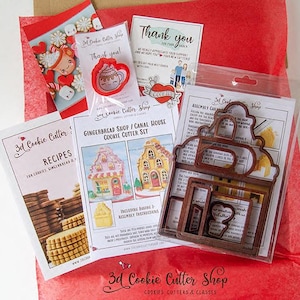 May include: A collection of cookie cutters and related items, including a gingerbread shop/canal house cookie cutter set, recipe cards, and thank you notes. The cutters are brown, and the packaging includes red and white accents.
