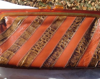 May include: A vintage brown and gold striped clutch bag with a clear plastic clasp.