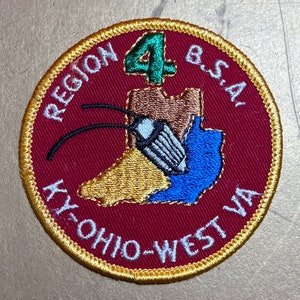 Puede incluir: Un parche bordado en rojo, blanco y azul con el texto "Region 4 B.S.A. Ky. Ohio-West Va." y un número verde "4" en el centro. El parche presenta un mapa estilizado de la región.