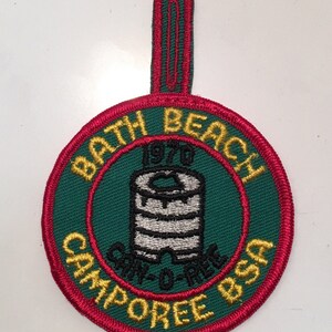 May include: A green and red embroidered patch with the text "Bath Beach 1970 Camp-O-Ree BSA" and a white and black illustration of a can of food.