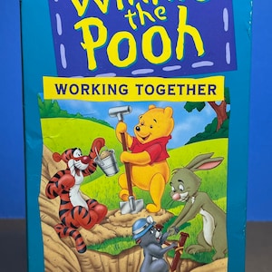 Puede incluir: Una cinta VHS con Winnie de Pooh y sus amigos trabajando juntos. La portada muestra a Winnie de Pooh, Tigger, Conejo y Piglet cavando un agujero. El texto en la portada dice "Disney Winnie de Pooh Trabajando juntos Aprendiendo".