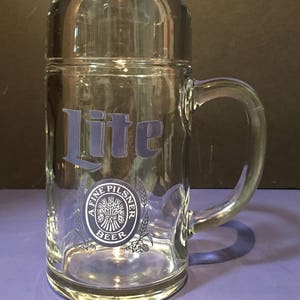 May include: A clear glass beer stein with a blue "Lite" logo and a white circle with the words "A Fine Pilsner Beer" and a wheat stalk design.