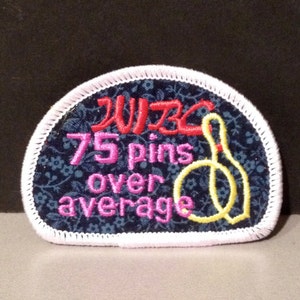 May include: A white and pink embroidered patch with a blue background. The patch features the text "WIBC 75 pins over average" and a yellow bowling pin graphic.