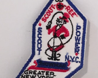 May include: A white embroidered patch with a blue border. The patch features a cartoon figure of a scout in a red uniform jumping rope. The text "Scout-O-Ree" is written in a circle around the figure. The text "Bowler NYC" is written below the figure. The text "Greater New York Councils" is written below the circle.