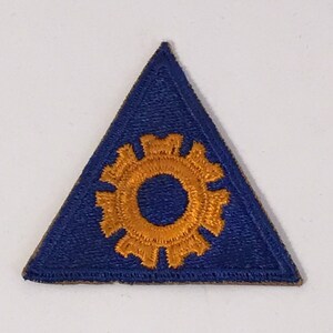 May include: A blue triangular patch with a gold gear-like symbol in the center.