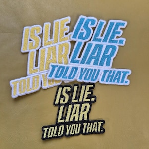 May include: Embroidered patches with the phrases "IS LIE LIAR TOLD YOU THAT" in yellow, blue, and black. The patches are on a gold-coloured background. The patches are a fun and unique accessory.