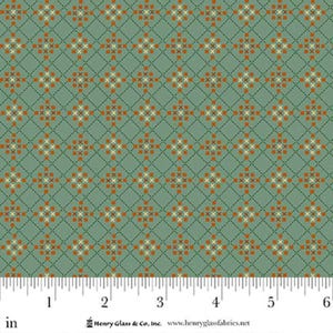 May include: A fabric with a repeating pattern of orange and cream cross-stitch-style designs on a muted green background. The design is arranged in a grid pattern with dashed lines. The fabric is measured in inches.