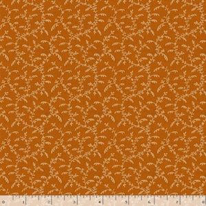 May include: A burnt orange fabric featuring a repeating pattern of light beige, delicate, winding vine-like stems with small leaves. A white ruler is visible at the bottom edge, showing measurements in inches from zero to eight inches.