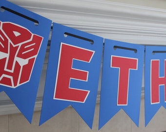 May include: A blue and red banner with the name "ETHAN" and a Transformers logo.