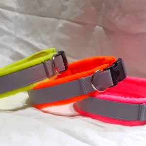 May include: Three dog collars in different colors: neon yellow, orange, and pink. Each collar has a gray reflective strip and a black buckle.