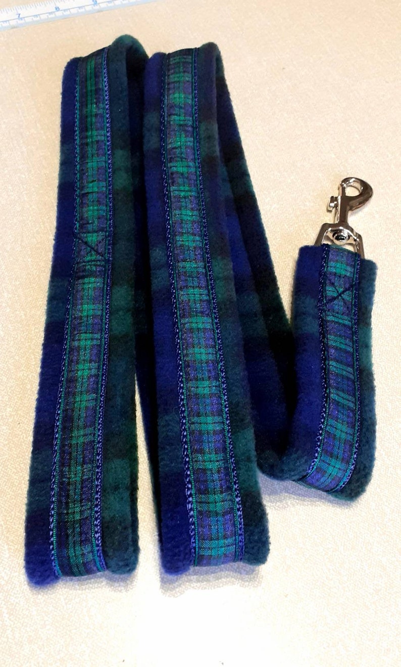 Pu&ograve; includere: Un guinzaglio per cani con motivo scozzese blu e verde, con manico abbinato. Il guinzaglio &egrave; realizzato in un tessuto morbido e felpato e presenta un moschettone in metallo color argento. Il motivo scozzese include sfumature di blu, verde e viola.