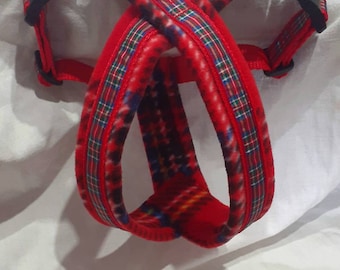 May include: Red dog harness with a plaid pattern and black buckles. The harness has a metal clip for attaching a leash.