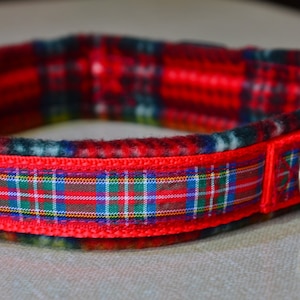 May include: Red and green plaid dog collar with a black buckle and a silver D-ring.