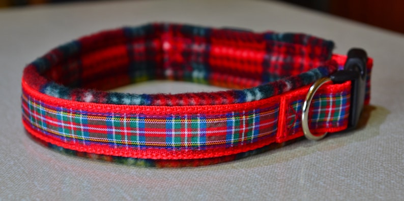 May include: Red and green plaid dog collar with a black buckle and a silver D-ring.