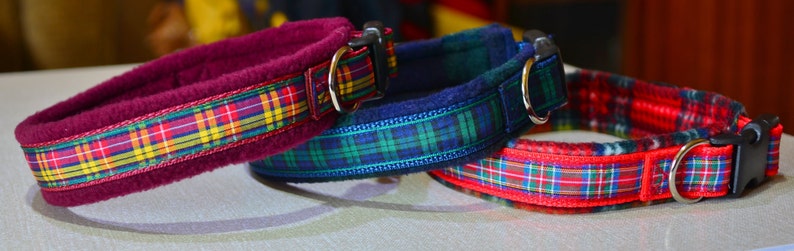 May include: Three dog collars with plaid patterns. The collars are red, blue, and burgundy with white and yellow accents. The collars are made of fleece and have a buckle closure.
