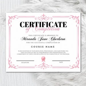 Peut inclure: Un certificat de fin d'études avec une bordure rose et des ornements décoratifs. Le texte "CERTIFICATE of Completion" est en haut, avec de l'espace pour un nom et un cours. Un stylo argenté repose sur le côté gauche de l'image.