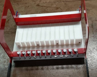 May include: A red metal frame with white plastic dividers and silver knobs. The frame is used for making candles.