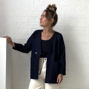 May include: A navy blue denim jacket with a single button closure and two large pockets. The jacket has a relaxed fit and is made of a soft, comfortable fabric.