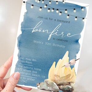 May include: A blue watercolor invitation with string lights and a campfire illustration. The text reads "Join us for a backyard bonfire to celebrate Mark's 30th Birthday". The invitation includes the date, time, and location of the event.