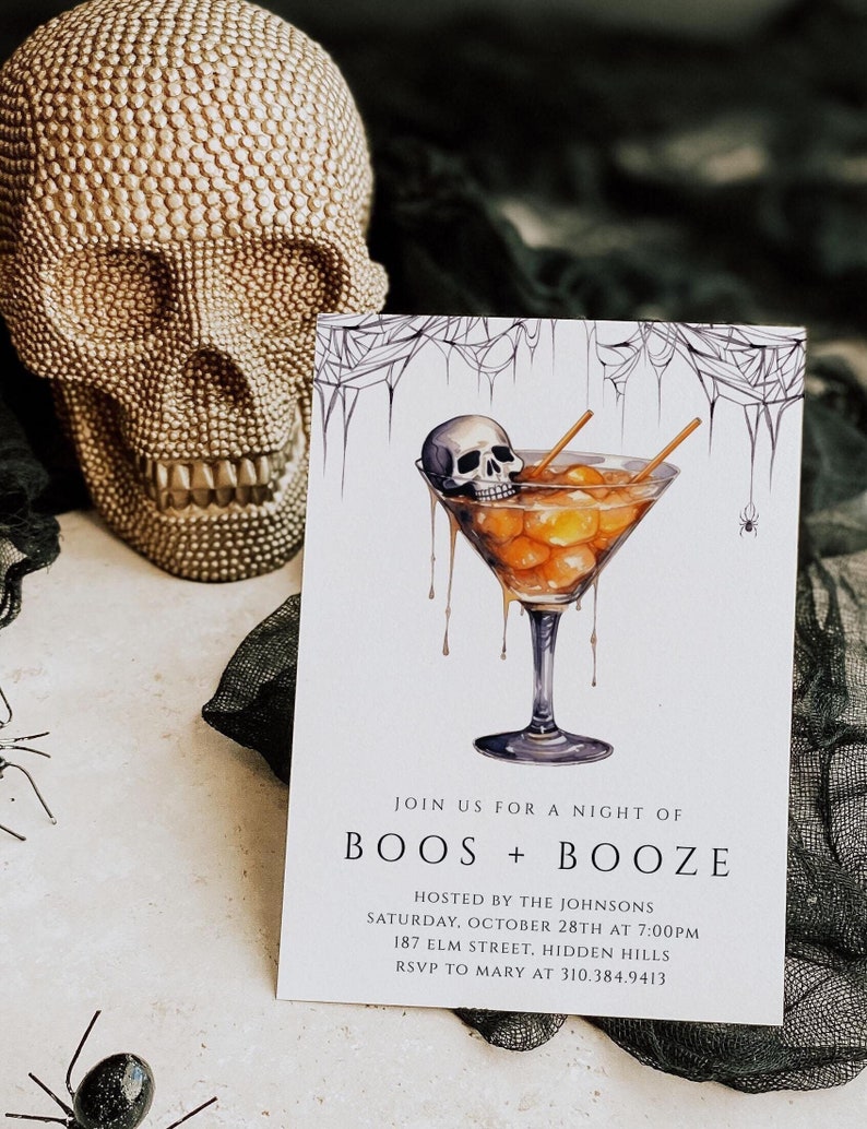 Pu&ograve; includere: Invito a una festa di Halloween con un teschio in un bicchiere da martini pieno di ciliegie maraschino arancioni e gialle. Il testo recita "Join us for a night of Boos + Booze" e include i dettagli della festa: Hosted by the Johnsons, sabato 28 ottobre alle 19:00, 187 Elm Street, Hidden Hills, RSVP to Mary at 310.384.9413.