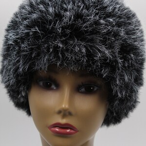 May include: A black and white fluffy hat with a round shape. The hat is made of a soft, fluffy material.