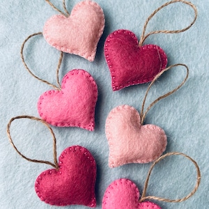 May include: Six felt heart ornaments in pink and red with twine loops for hanging.