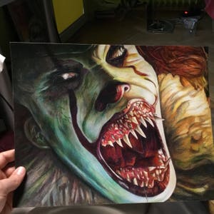 May include: A close-up drawing of a clown with sharp teeth and a wide open mouth. The clown's face is green and yellow with red and black makeup. The drawing is done in colored pencil.