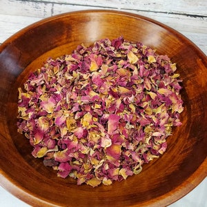 May include: A wooden bowl filled with dried rose petals. The petals are a mix of pink and brown.