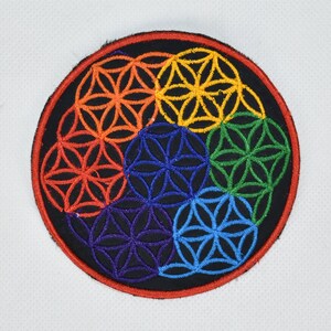 May include: A colourful embroidered patch featuring a flower of life design in red, orange, yellow, green, blue and purple.