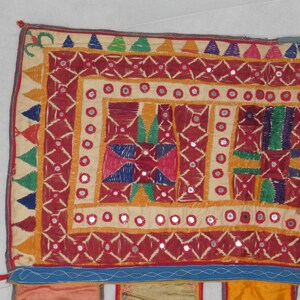 Puede incluir: Un tapiz de pared textil colorido con bordados intrincados y adornos de espejo. El dise&ntilde;o presenta patrones geom&eacute;tricos en tonos de rojo, naranja, amarillo, verde, azul y morado.