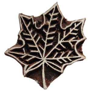 May include: A wooden block carving of a maple leaf, with a detailed design of veins and a brown colour.