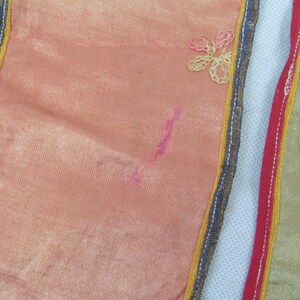 Puede incluir: Primer plano de una tela rosa con ribete dorado y azul. La tela tiene un dise&ntilde;o floral bordado.