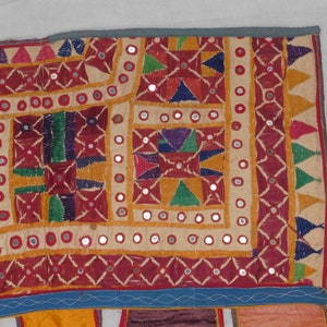 Puede incluir: Un tapiz de pared textil colorido con bordados intrincados y adornos de espejo. La tela es un mosaico de diferentes colores y patrones, incluyendo rojo, amarillo, verde, azul y morado. El tapiz est&aacute; decorado con peque&ntilde;os espejos redondos que est&aacute;n cosidos en la tela.