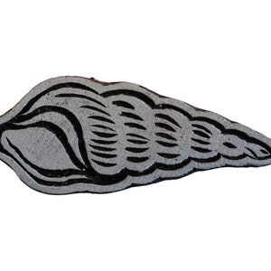 May include: A wooden printing block carved with a detailed design of a seashell. The block is grey with black lines and is ready to be used for printing.