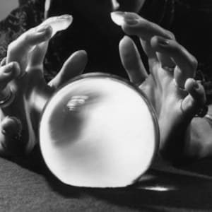 Può includere: Un paio di mani tiene un grande globo di vetro trasparente, spesso utilizzato per la divinazione o la divinazione.