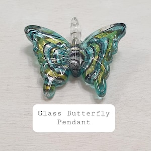 May include: A glass butterfly pendant with blue, green and gold swirling patterns. The pendant has a clear glass loop for hanging.