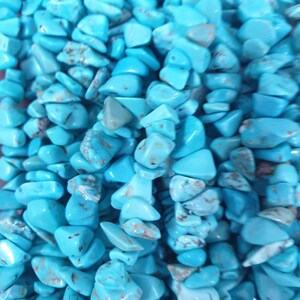 May include: A strand of turquoise gemstone beads, each bead is a unique, irregular shape with a light blue colour and a slightly mottled texture.