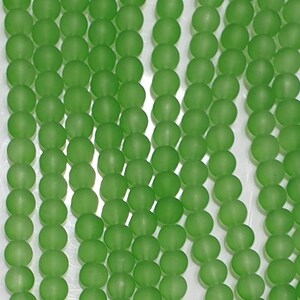 May include: A strand of round, frosted green glass beads. The beads are uniform in size and have a matte finish.