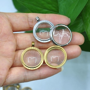 May include: A collection of circular floating locket pendants featuring clear glass faces and metal frames in silver and gold tones. The lockets are designed with a screw-top mechanism and include small metal loops at the top for attachment.