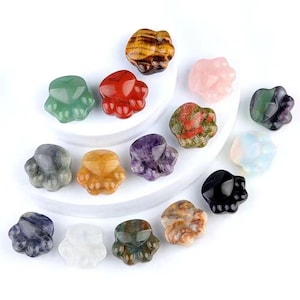 Op de afbeelding: Assortiment van 14 pootvormige kristallen bedels in verschillende kleuren en patronen, waaronder groen, rood, roze, bruin, paars, zwart, wit en veelkleurig.