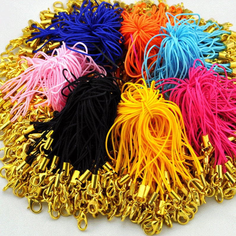 May include: A large assortment of colorful string cords with gold metal clasps. The cords are in various colors, including pink, blue, yellow, orange, black, and red.