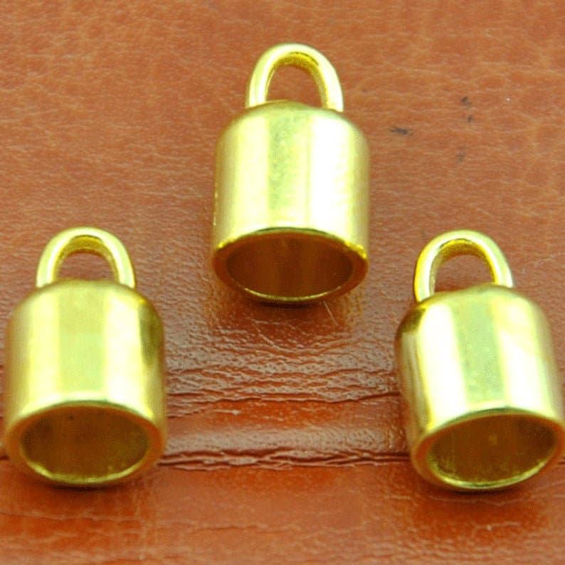 May include: Three gold-colored metal end caps with a loop at the top. The end caps are cylindrical in shape and have a smooth, shiny finish.