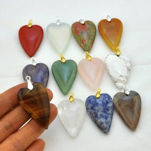 Puede incluir: Surtido de 12 colgantes de piedras preciosas en forma de corazón con anilla de oro. Los colgantes están hechos de varias piedras, incluyendo amatista, cuarzo rosa, ojo de tigre y cuarzo transparente.